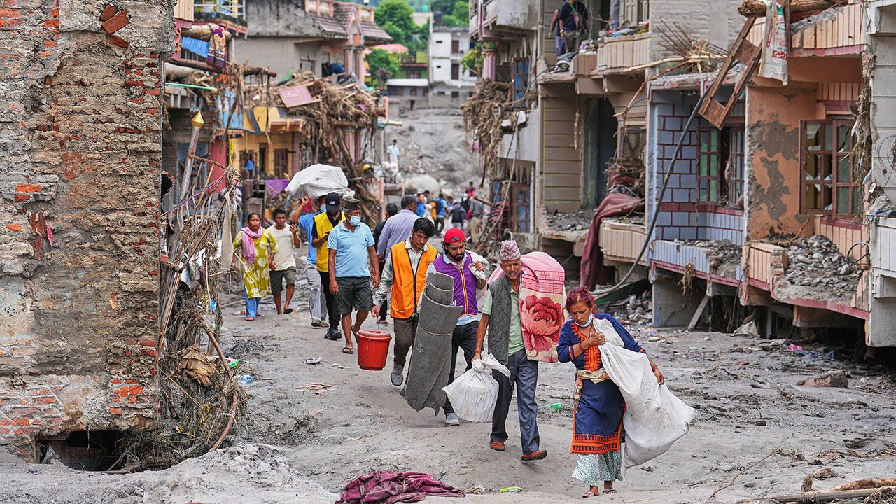 Residents carry their belongings salvaged from their damaged homes filled with mud and debris in Devighat, in Nepal's Nuwakot district, Saturday, Aug. 29, 2026, following the Aug. 26 flash floods.