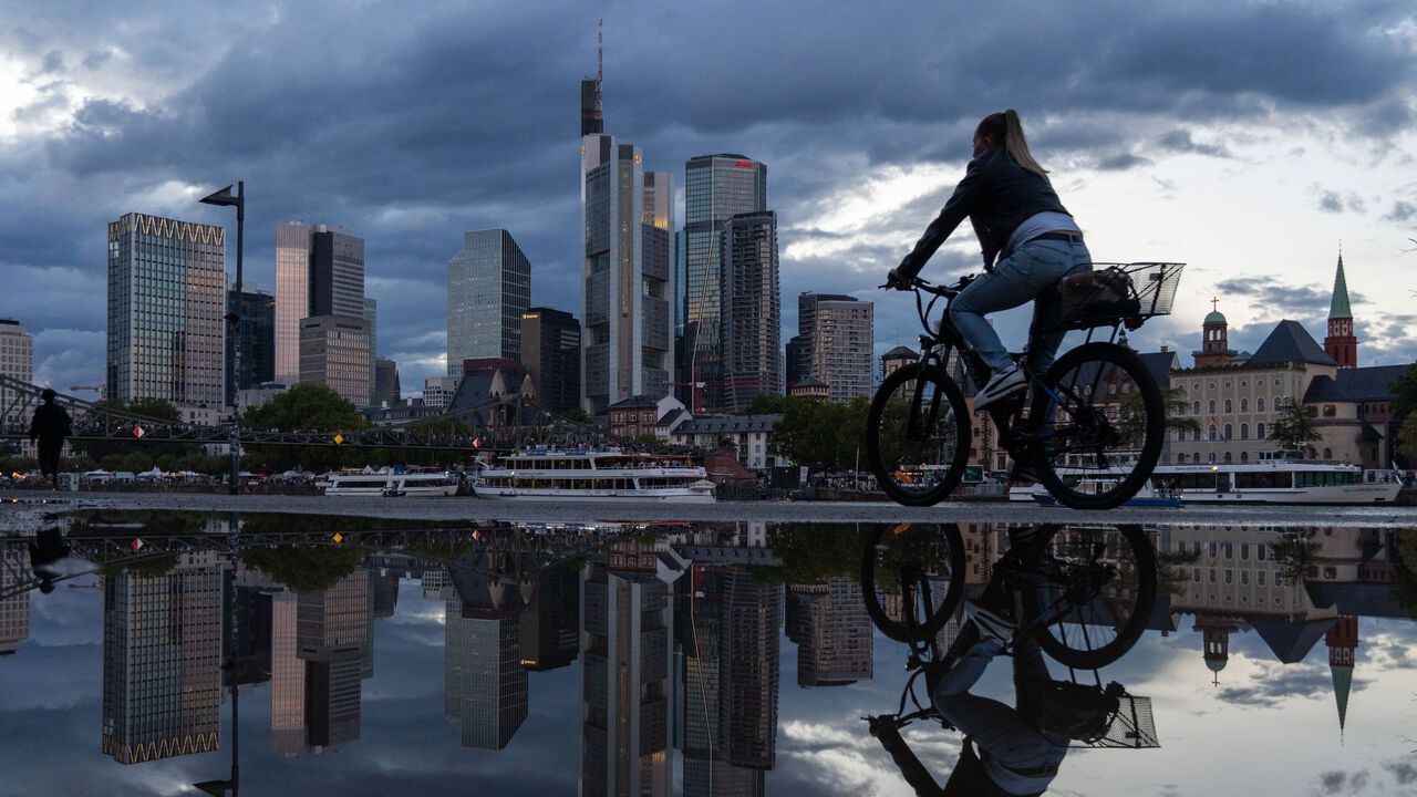 A cyclist rides past a puddle reflecting the financial district skyline after a stormy day in Frankfurt am Main, Germany.