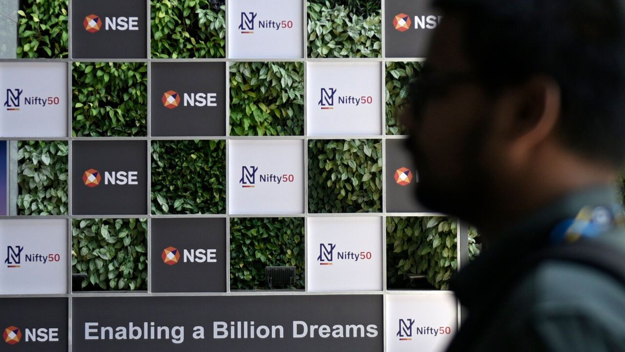 The logo of Nifty 50 and the National Stock Exchange (NSE) is seen at the NSE building in the business district of Mumbai, India - a close up shot of a man's head in the foreground to the right of the image.