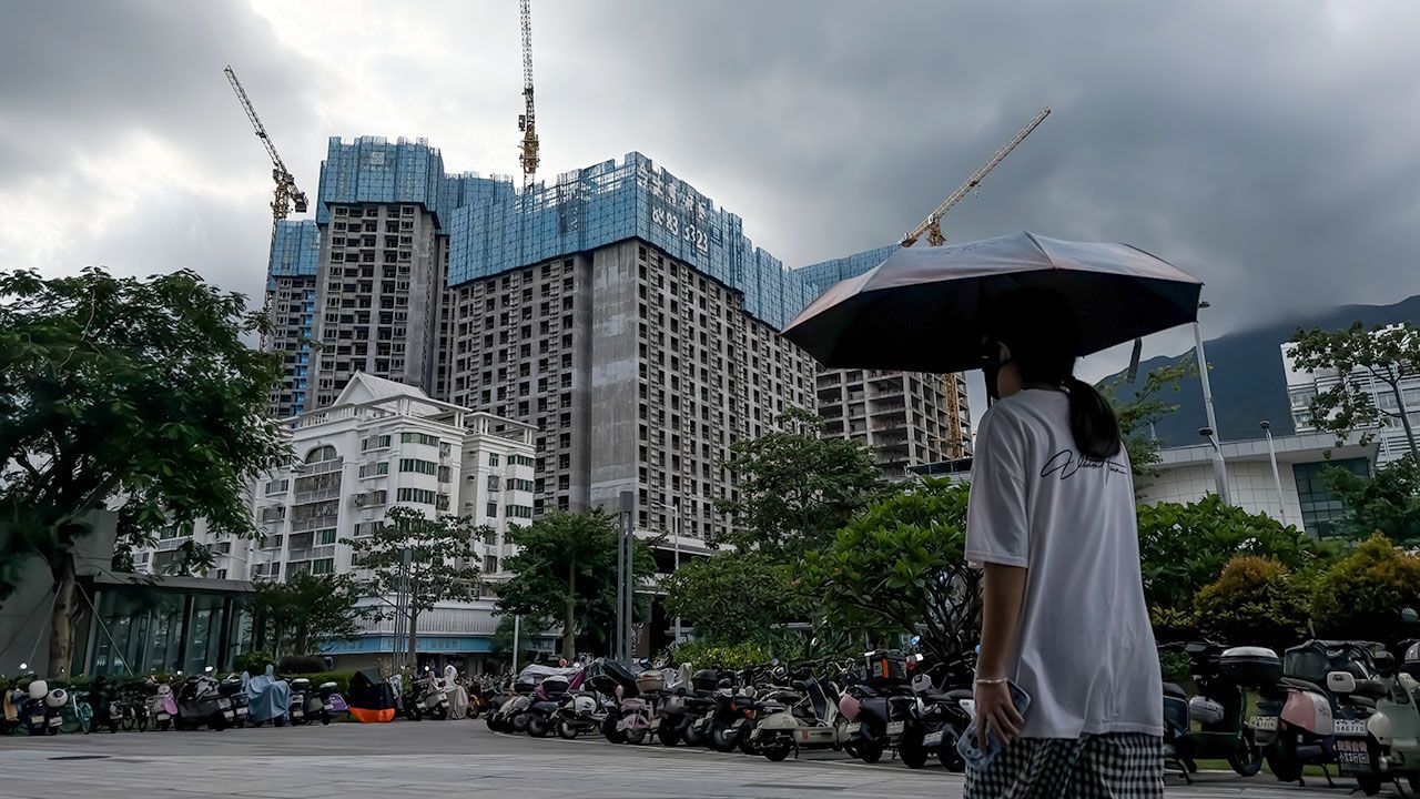 A pedestrian walks past residential buildings under construction in Shenzen