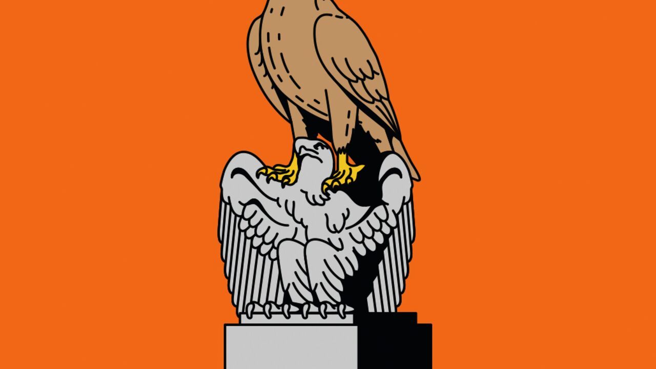A brown eagle stands on a grey eagle statue, set against an orange background