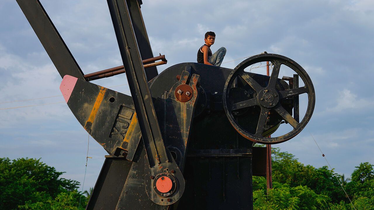 A boy sits on an inactive oil pumpjack in Cabimas, Venezuela.