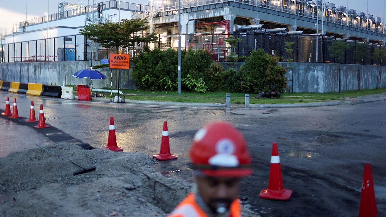 A worker directs traffic as a road is dug up to lay cables outside a data centre in Johor state, which has become Southeast Asia's fastest-growing data centre hub, at Gelang Patah, Malaysia May 7, 2026.