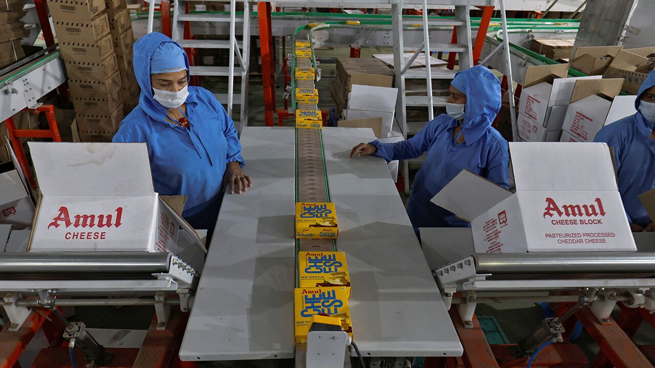 Employees work to fill boxes with Amul Processed Cheese packs going through a production line at an Amul satellite dairy in Khatraj village, in the western Indian state Gujarat, India, May 6, 2025.