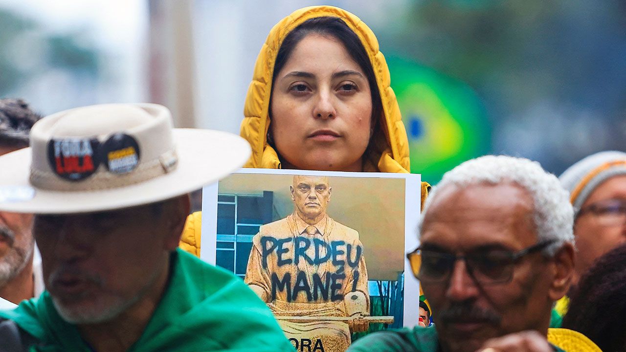 A supporter of Brazil's presidential candidate Flavio Bolsonaro holds a placard depicting Supreme Court Justice Alexandre de Moraes bearing the phrase "you lost, mane" during a rally