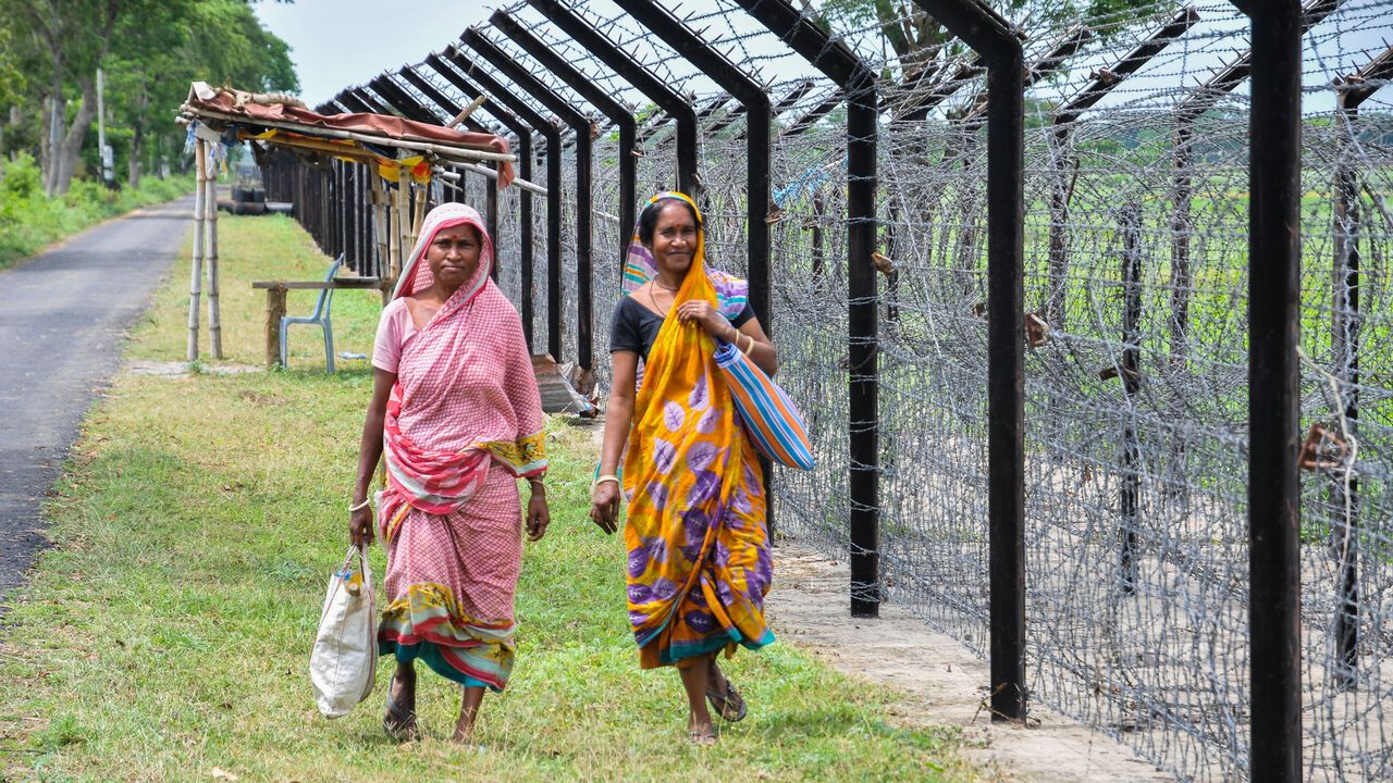 Two women in bright colourful clothing walking along the Indo-Bangladesh international border at Petrapole.