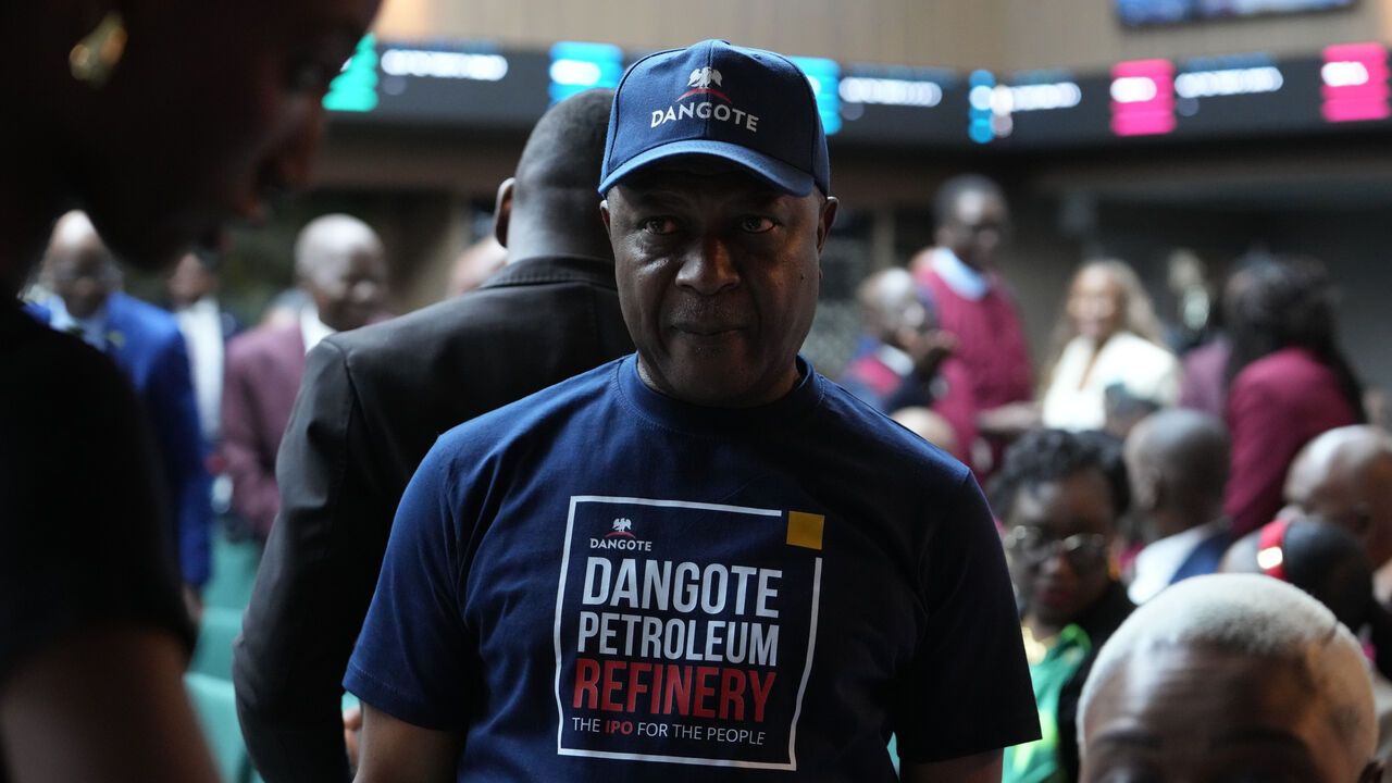 People attend the Opening Gong Ceremony of the Dangote Refinery Initial Public Offer at the Nigeria Stock Exchange in Lagos, Nigeria. A man wears a branded Dangote cap and t-shirt.