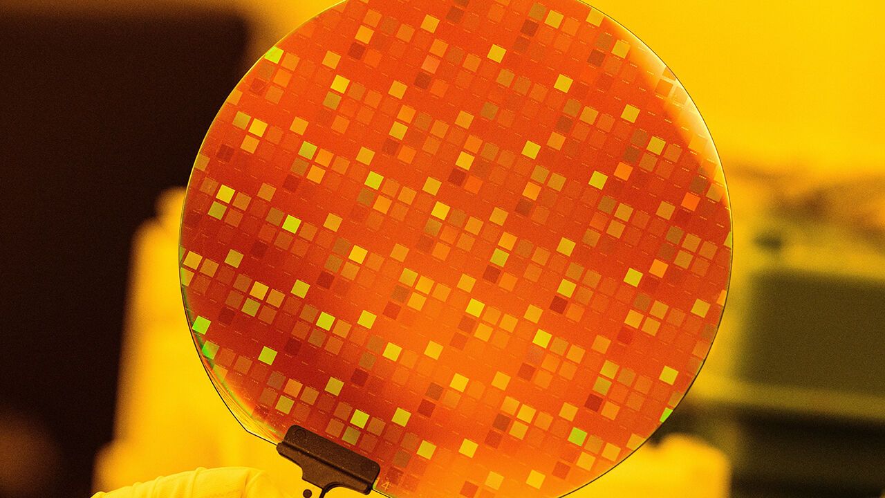 A semiconductor wafer is help by a gloved hand