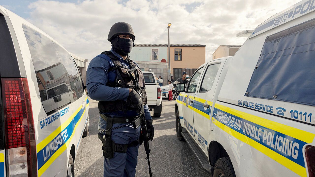 A South African policeman secure the perimeter while a house is searched for guns, drugs and counterfeit goods