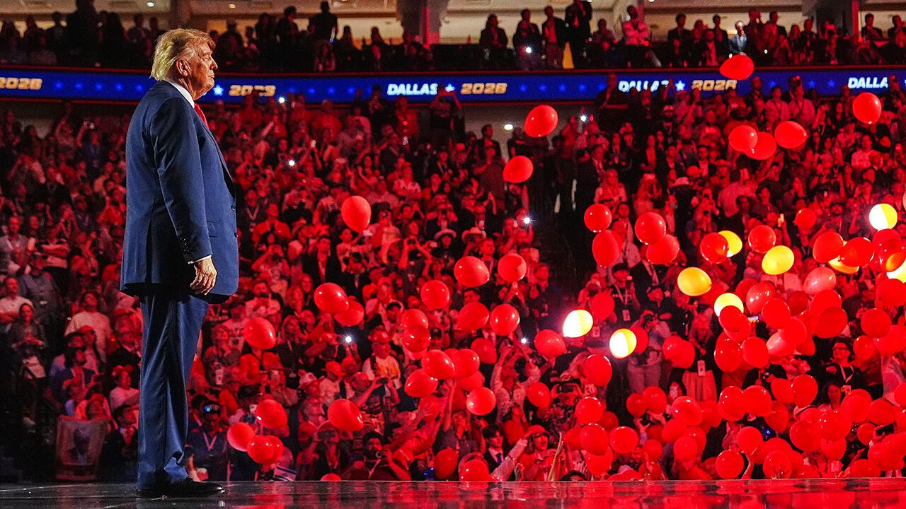 President Donald Trump stands on stage as red balloons fall at the Republican convention.