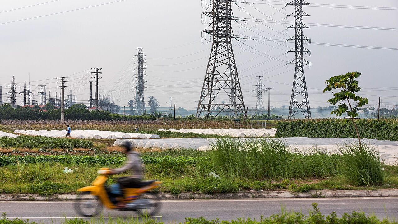 A man rides a motorbike past an electric power substation in Vietnam, Vinh Phuc Province.