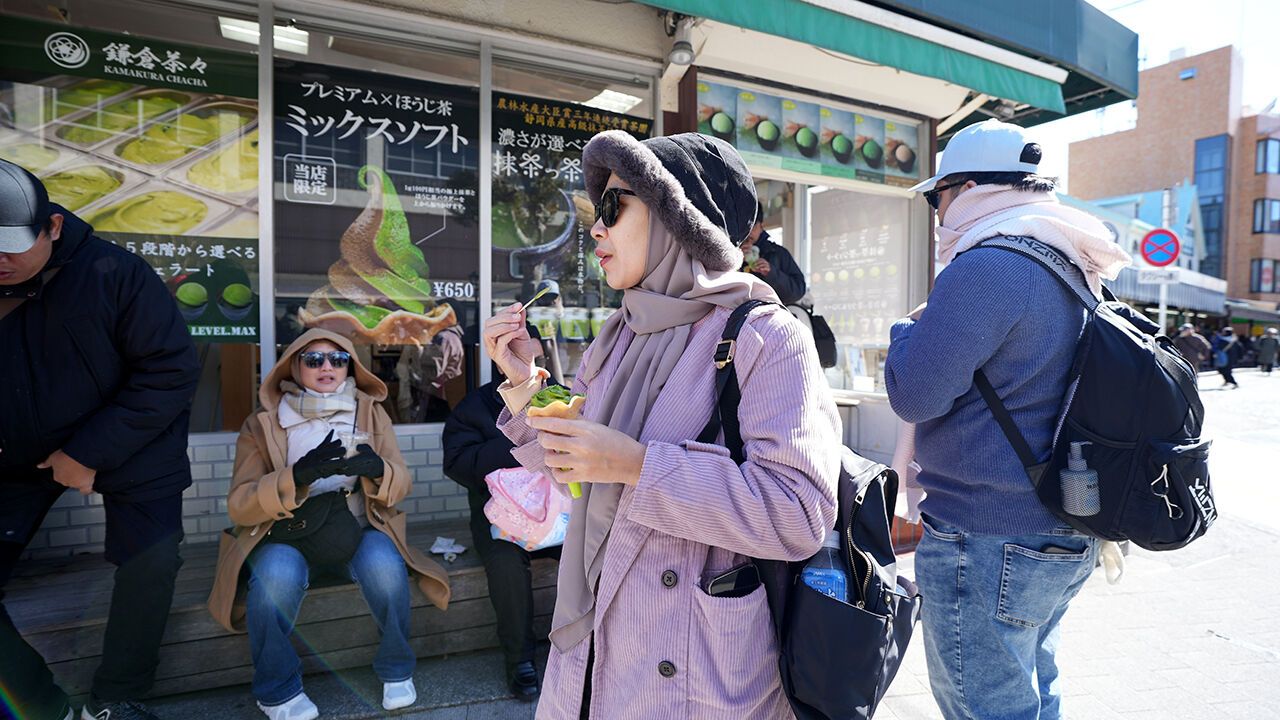 A tourist woman is enjoying a matcha ice cream during a hot day, Tokyo, Japan.