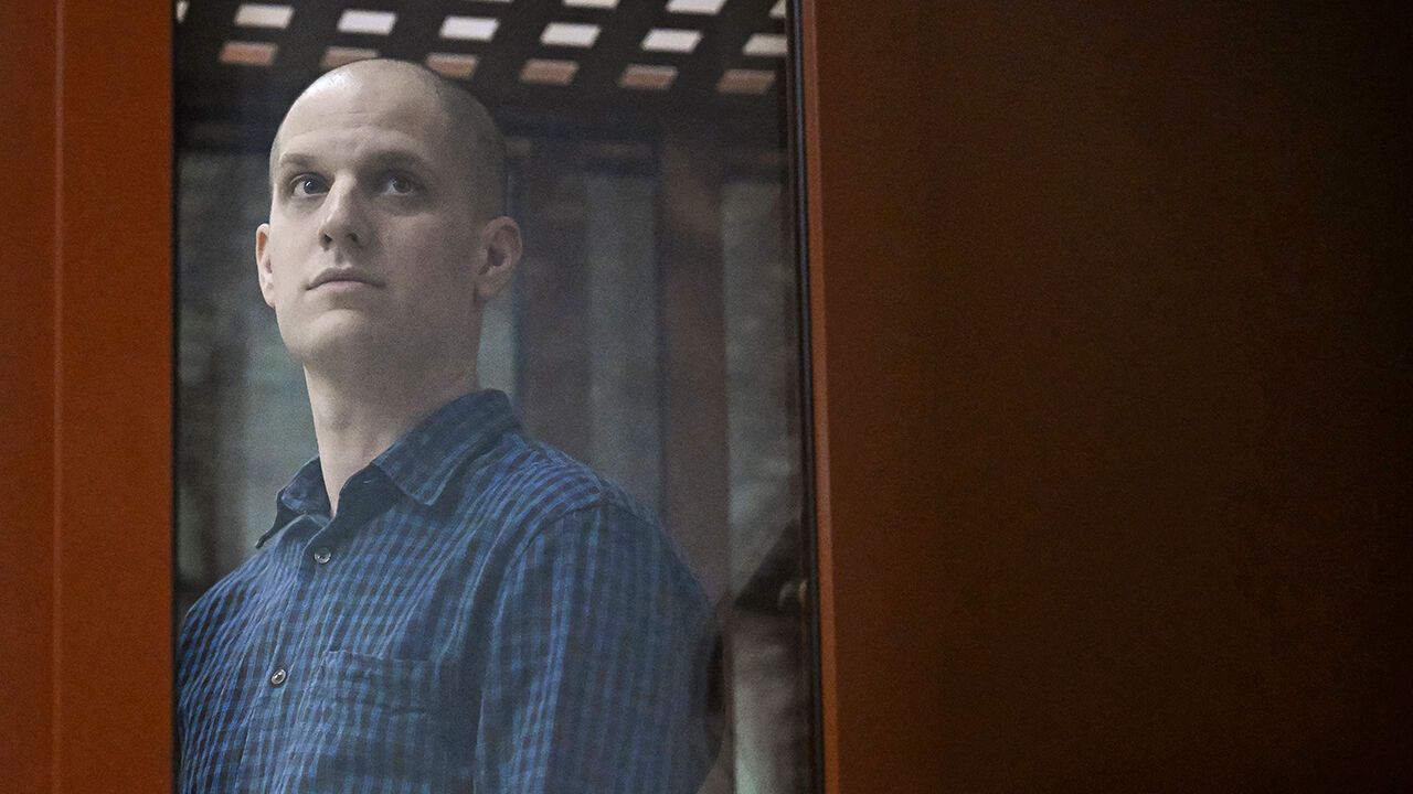 Evan Gershkovich looks out from inside a glass defendants' cage prior to a hearing.