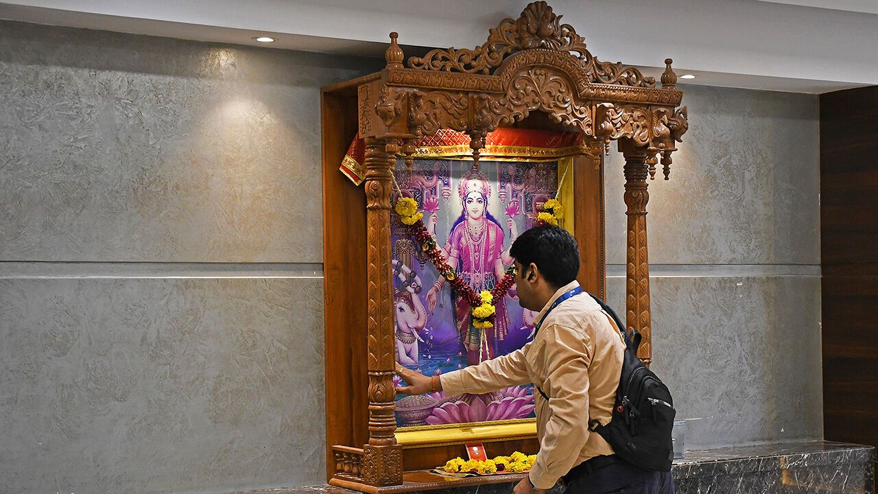 A man prays near the photo of goddess Lakshmi, the goddess of wealth inside the Bombay Stock Exchange (BSE) building in Mumbai.