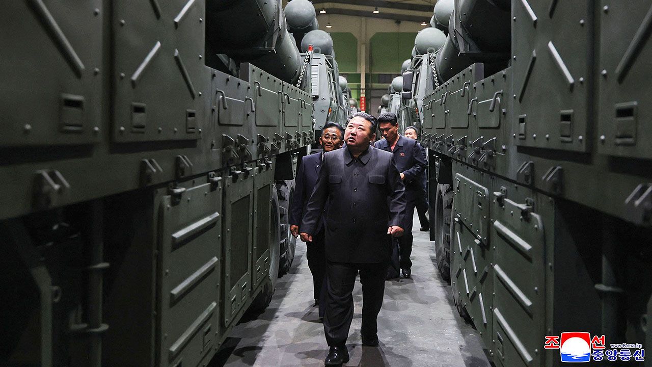 North Korean leader Kim Jong Un inspecting multiple rocket launcher vehicles at a munitions factory