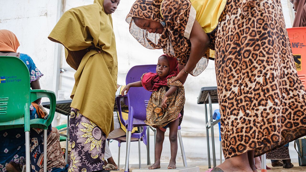 A mother weighs her malnourished child in Maiduguri, Nigeria