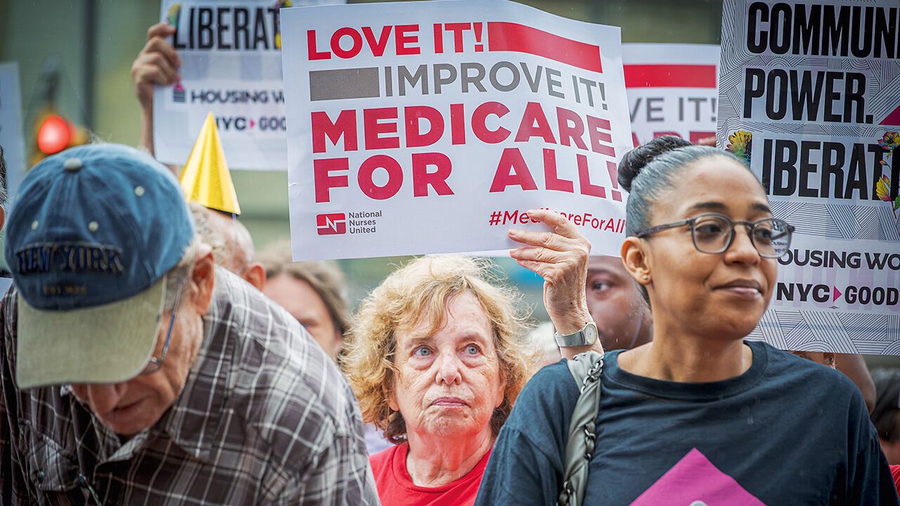 People protest holding placards reading 'Medicare for all'.
