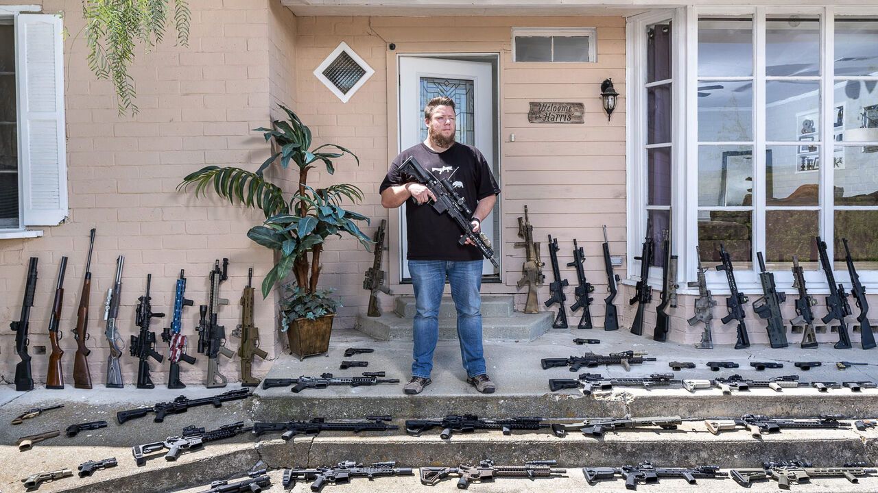Portrait of am man in America with his collection of guns.