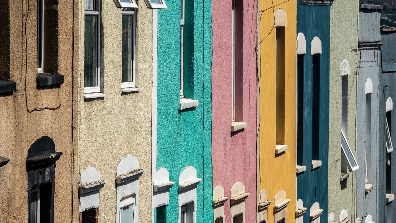Sunlight illuminates the front of a row of colourful Victorian-era houses in a terraced street in Bristol, England.