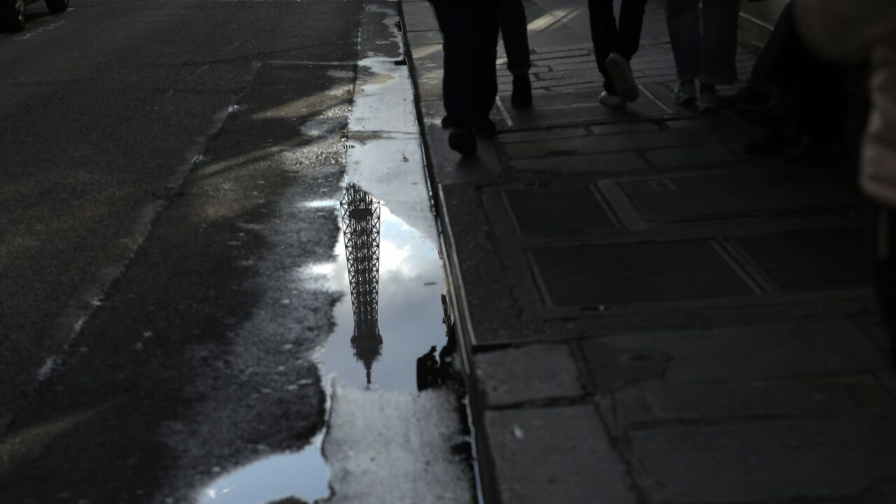 The Eiffel Tower is reflected in a puddle on a rainy day in Paris.