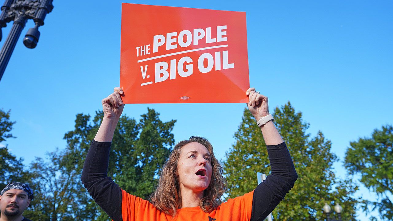 A protester holds a placard reading "Big Oil people outside the Supreme Court."