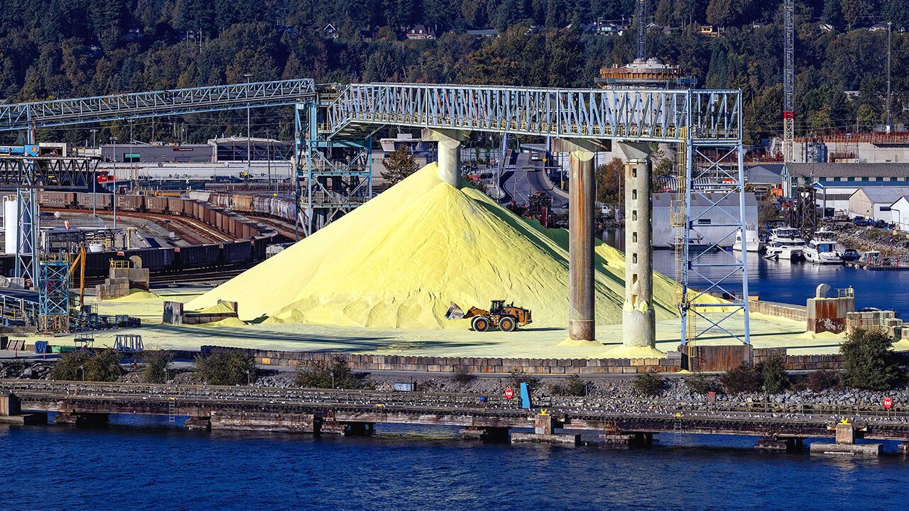 Piles of yellow sulphur at the North Vancouver Sulphur Works - North Vancouver, British Columbia, Canada - diggers in the foreground.