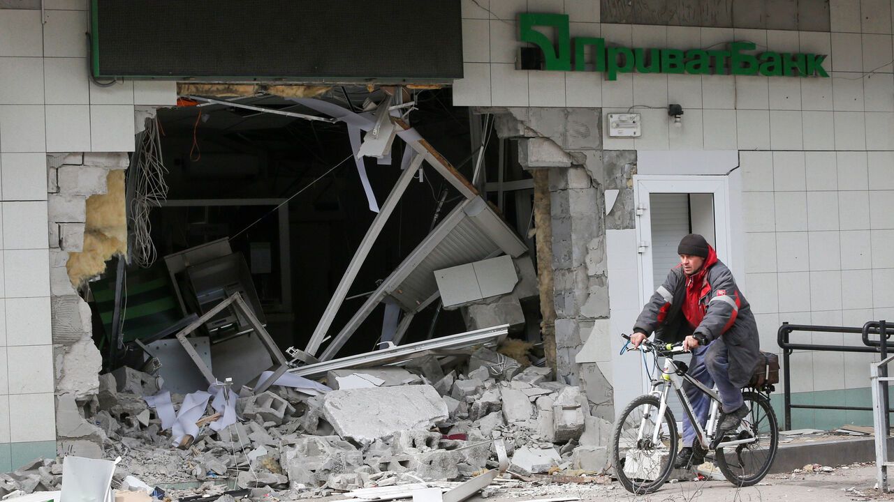 A man rides a bicycle near a branch of PrivatBank heavily damaged in the course of Ukraine-Russia conflict in the southern port city of Mariupol, Ukraine.