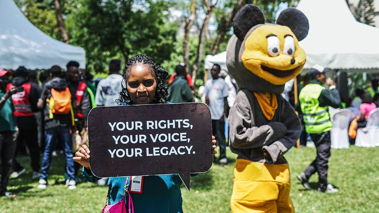 A participant poses for a photo while holding a placard during a continuous voter registration drive in Kenya