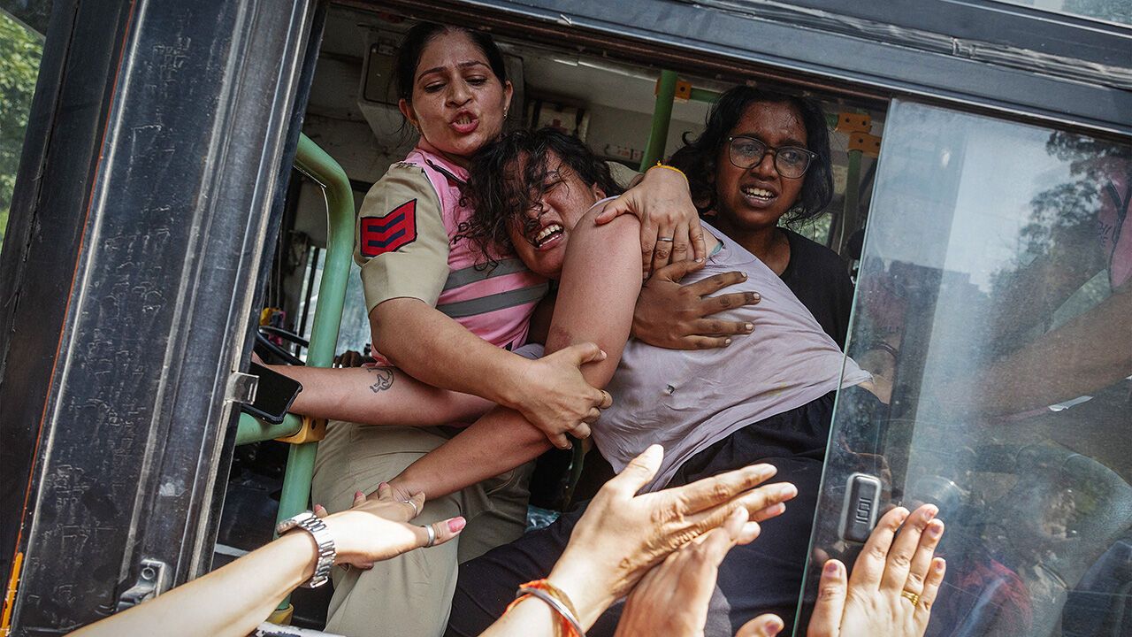 Policewomen try to stop a detained protestor to escape from a bus during a protest by the Cockroach Janta Party.