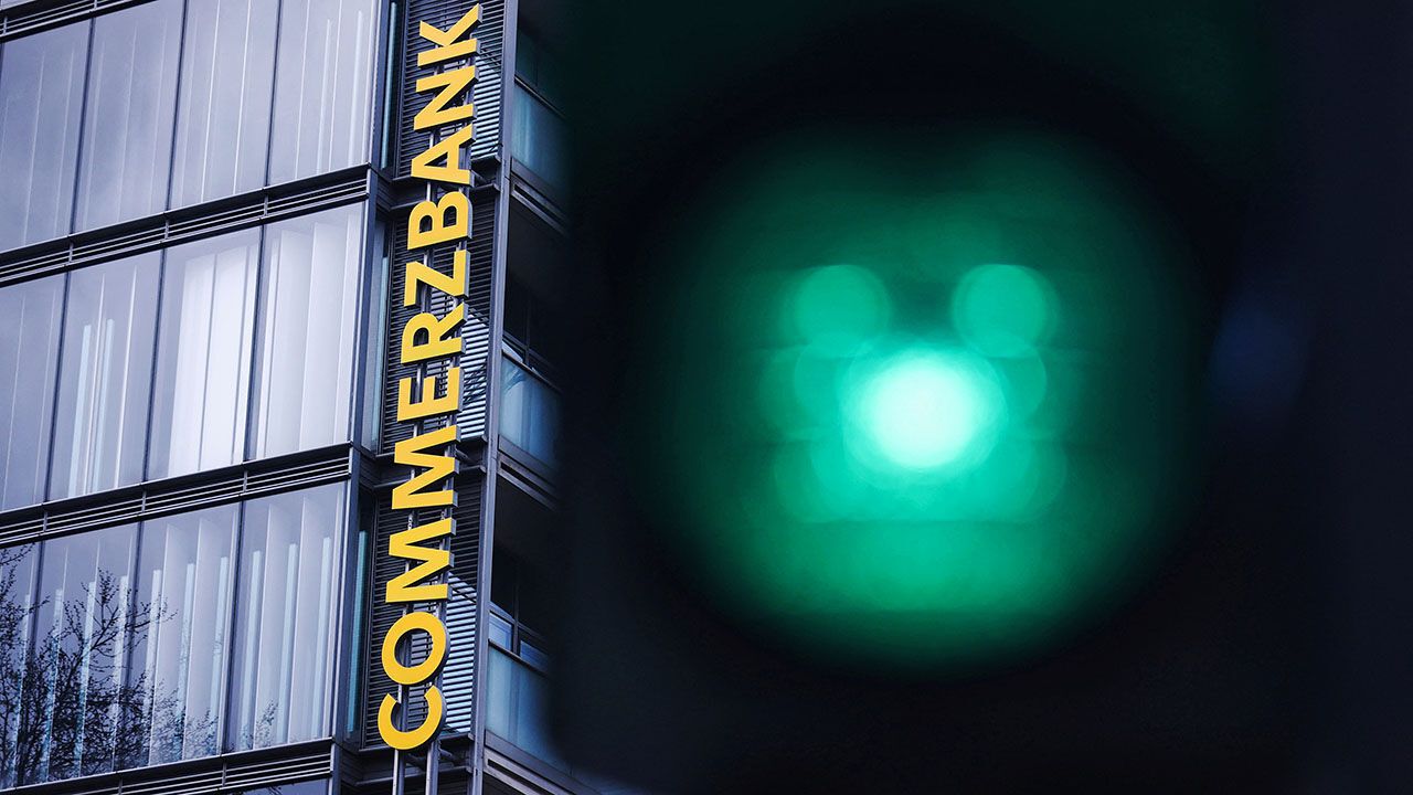 A traffic light glows green near a logo of Commerzbank at a branch in Cologne, Germany.