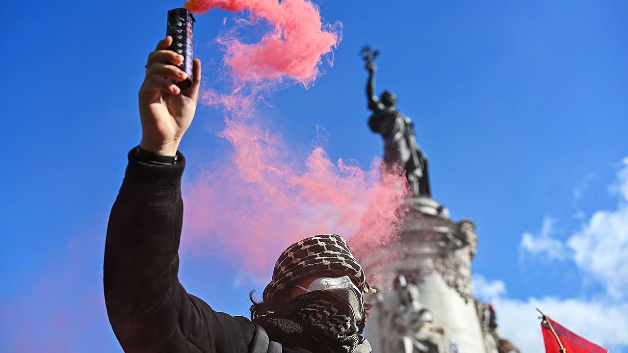 A protester raises a flair above his head in Place de la Republique