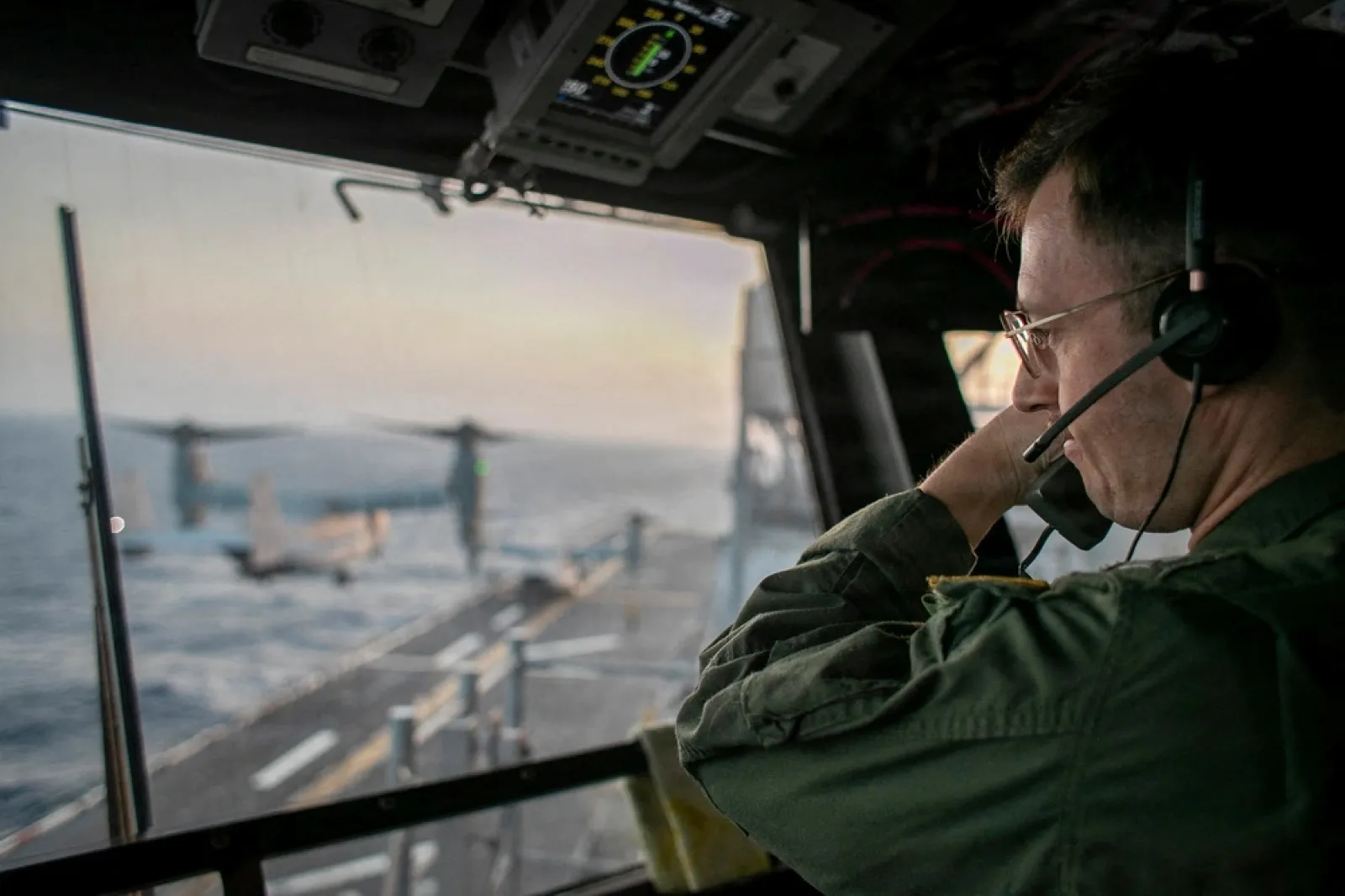 A naval officer aboard USS Tripoli (LHA 7) oversees flight operations from the control tower as the amphibious assault ship sails in the Arabian Sea. U.S. warships and aircraft deployed to the Middle East are enforcing the naval blockade against Iran whil